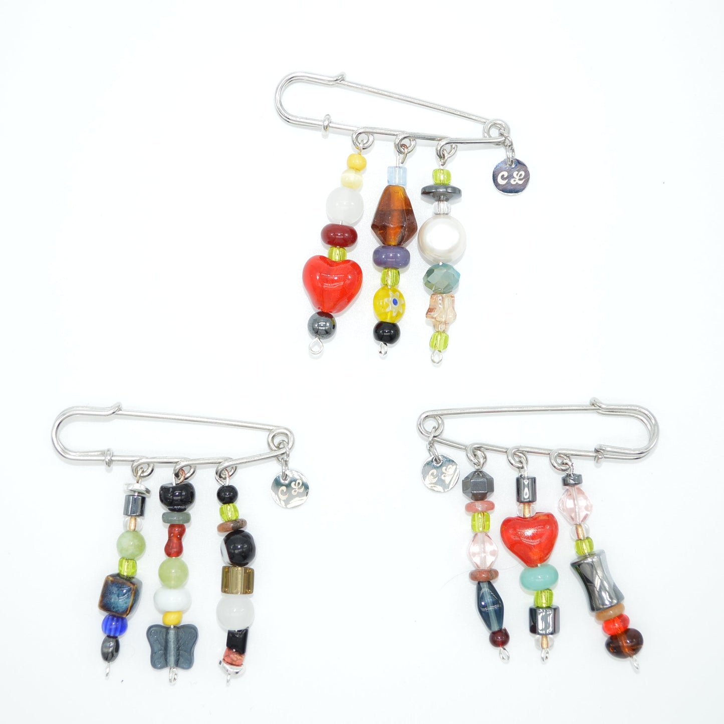 Set of three colorful brooches with beads on a white background