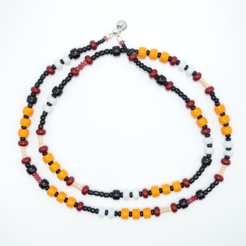 Beaded necklace with red, black, and orange beads on a white background