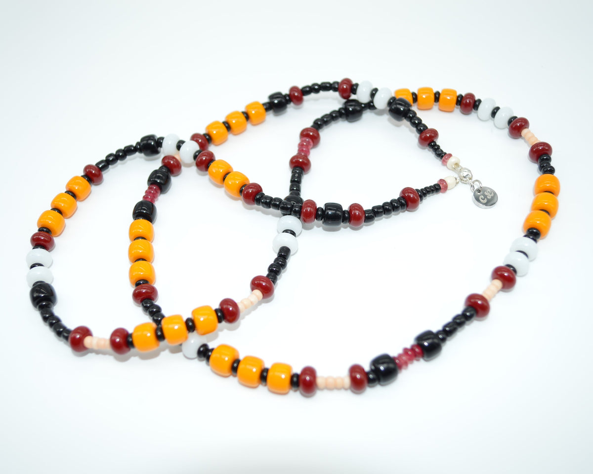 Beaded necklace with black, orange, and red beads on a white background