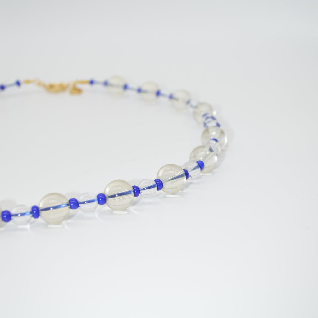 Necklace with blue and white beads on a light gray background