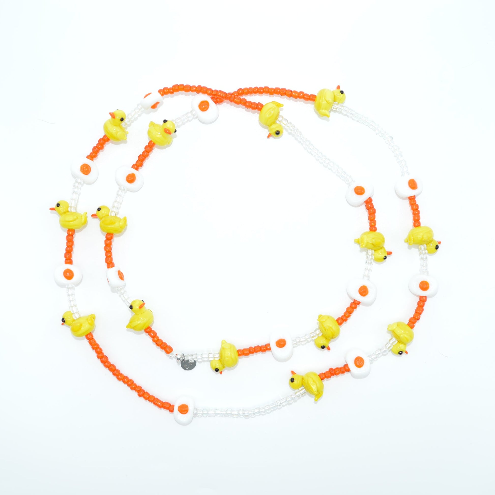 Neon orange and white necklace with small yellow birds on a light gray background