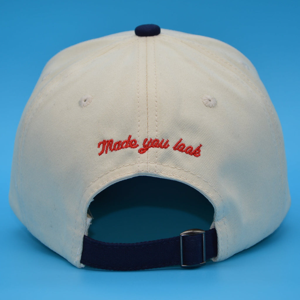 Beige cap with red text on a blue background
