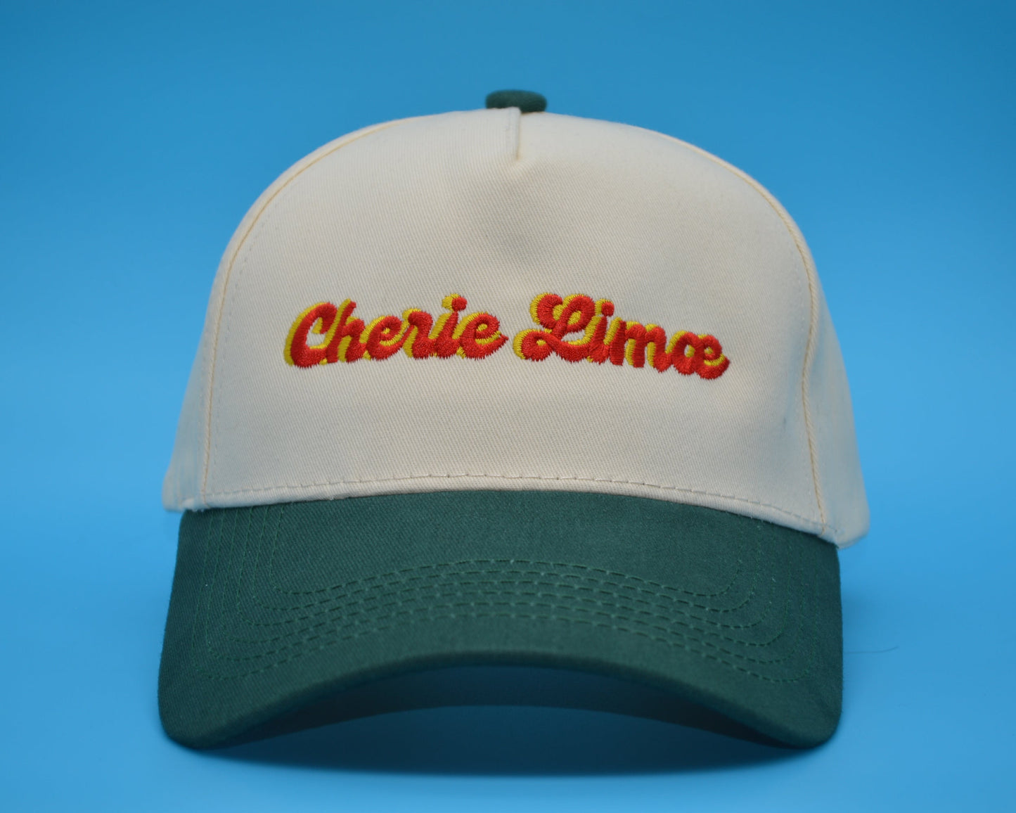 Beige and green cap with 'Cherie Lima' text on a blue background