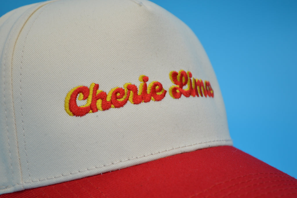 Cap with 'Cherie Line' embroidery on a blue background
