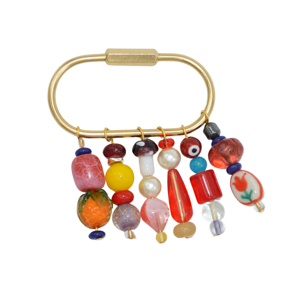Beaded brooch with colorful beads on a gold metal frame against a white background