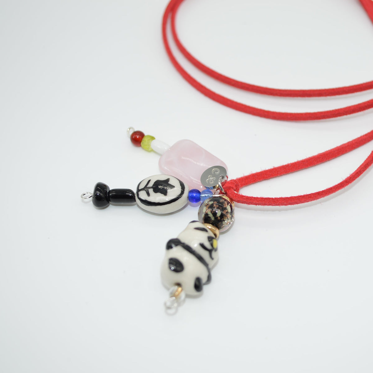 Red cord necklace with panda charm on a white background