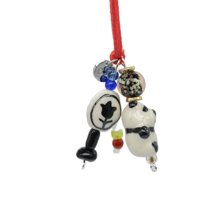 Panda-shaped charm on a red string with various beads against a gray background