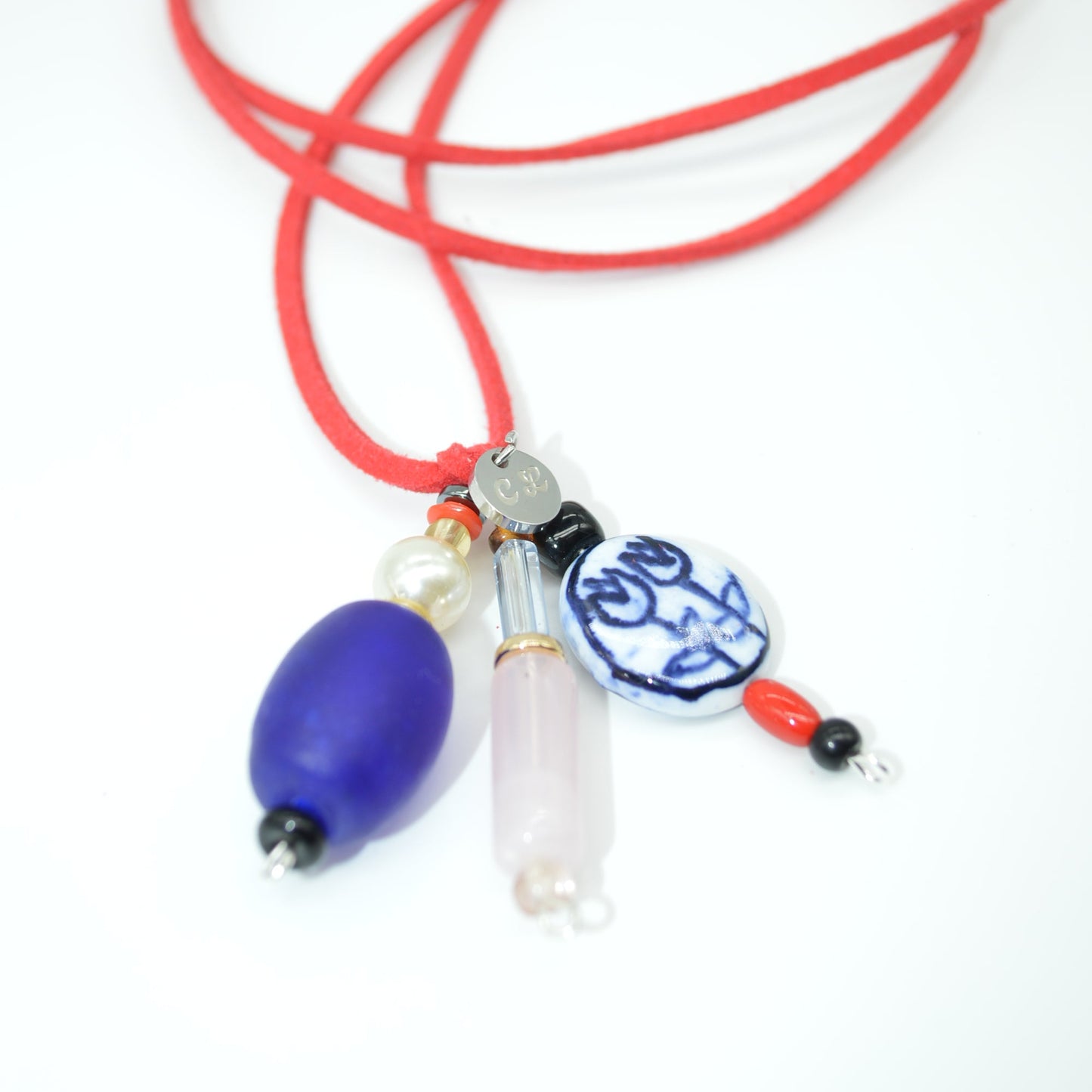 Necklace with red cord and various charms on a white background