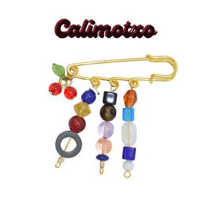 Colorful brooch with beads on a white background, branded 'Calimotxo'.