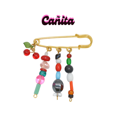 Colorful beaded brooch with a gold clasp on a white background, featuring the brand 'Cañita'.