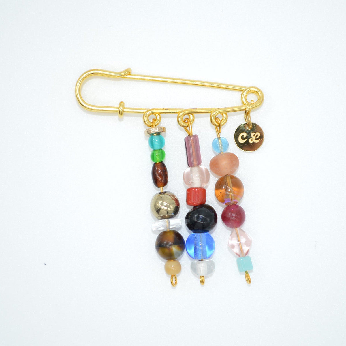 Gold brooch with colorful beads on a white background