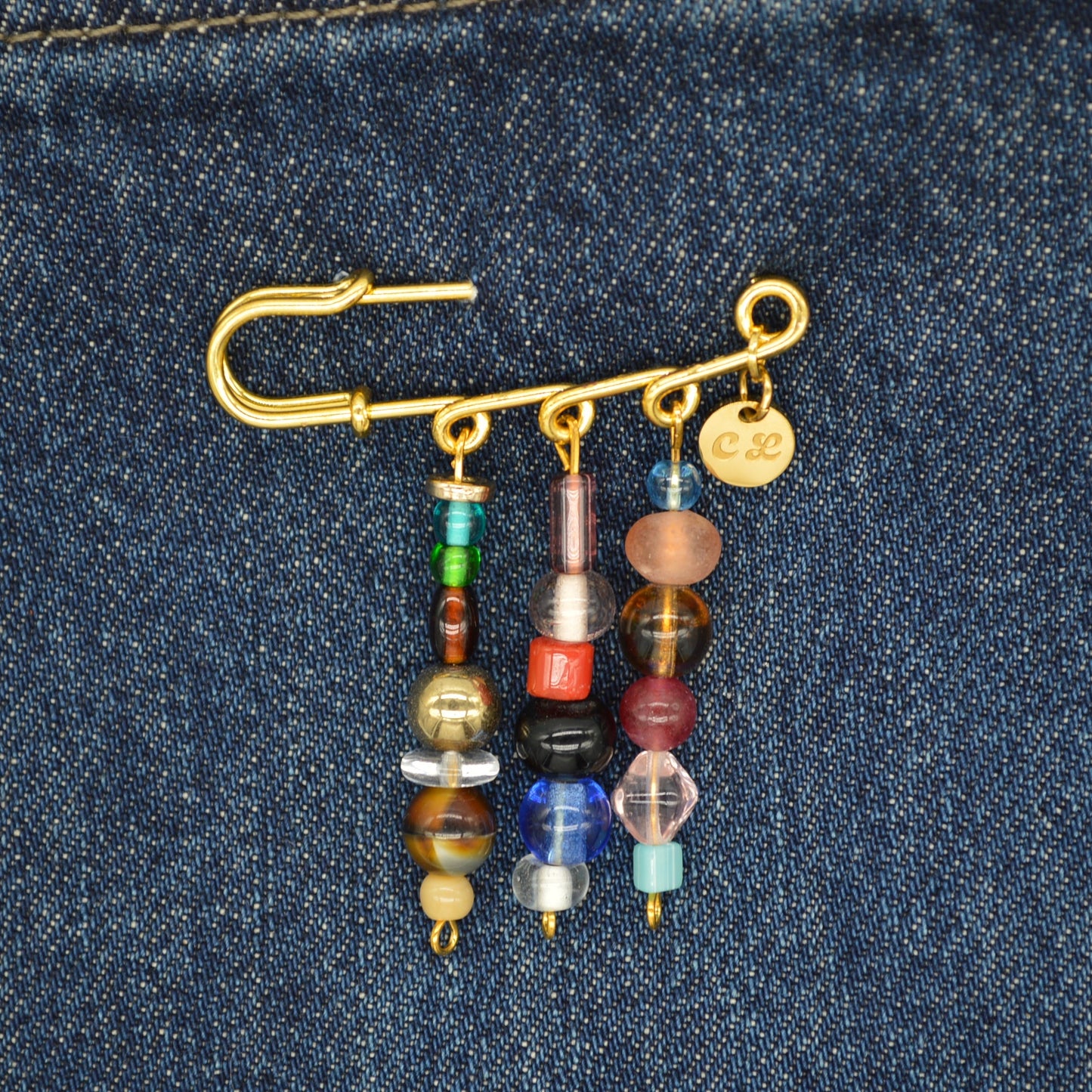 Gold brooch with colorful beads on a denim background