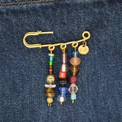 Gold brooch with colorful beads on a denim background