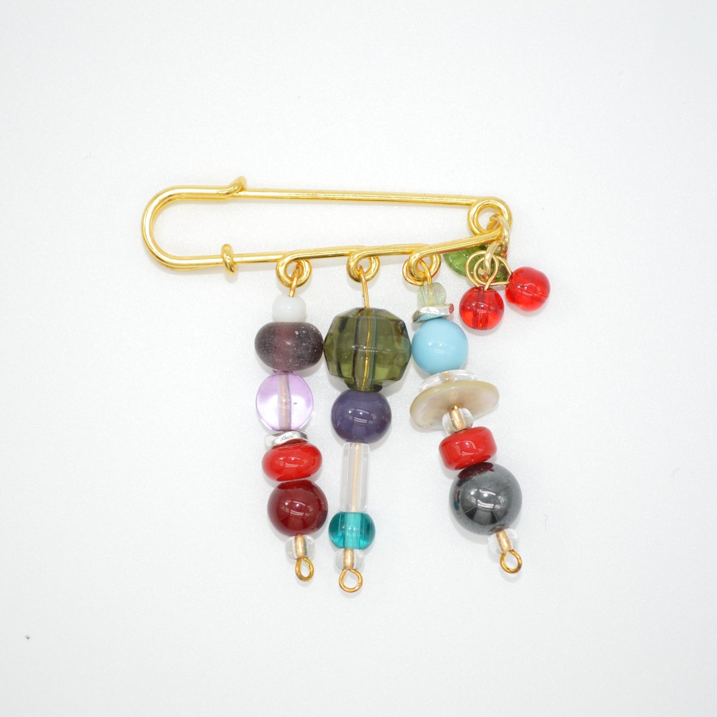 Colorful beaded brooch with a gold safety pin on a white background