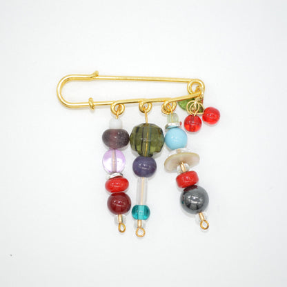 Colorful beaded brooch with a gold safety pin on a white background
