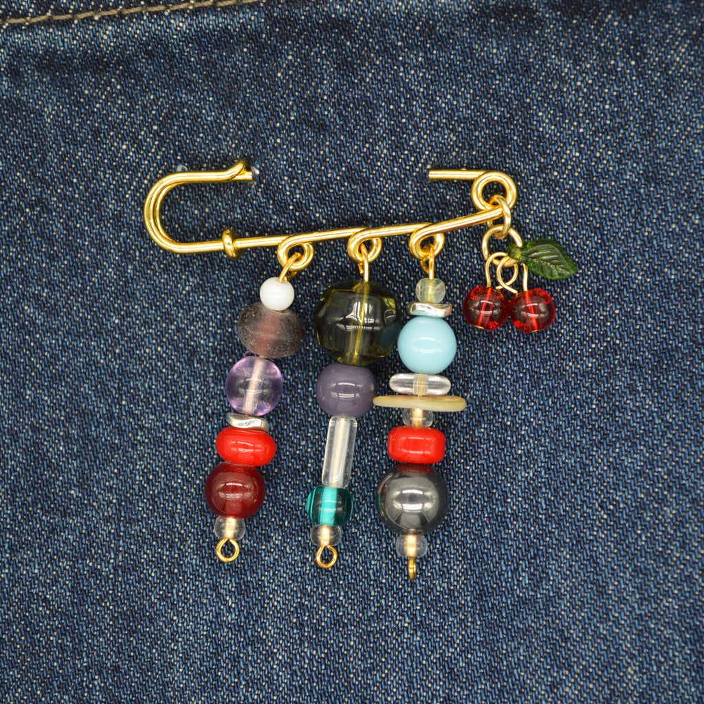 Decorative brooch with beads and charms on a denim background