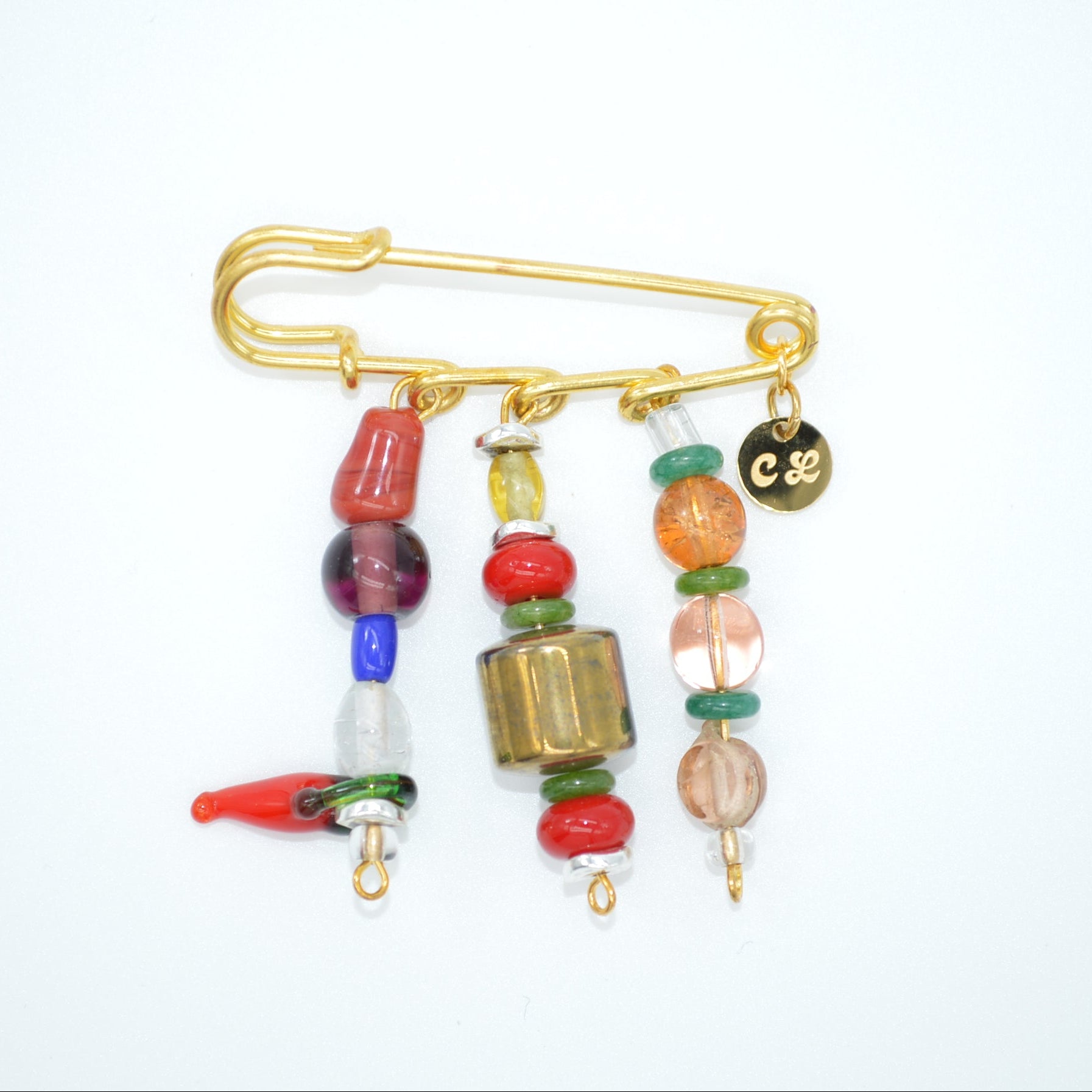 Colorful beaded brooch with a gold safety pin on a white background