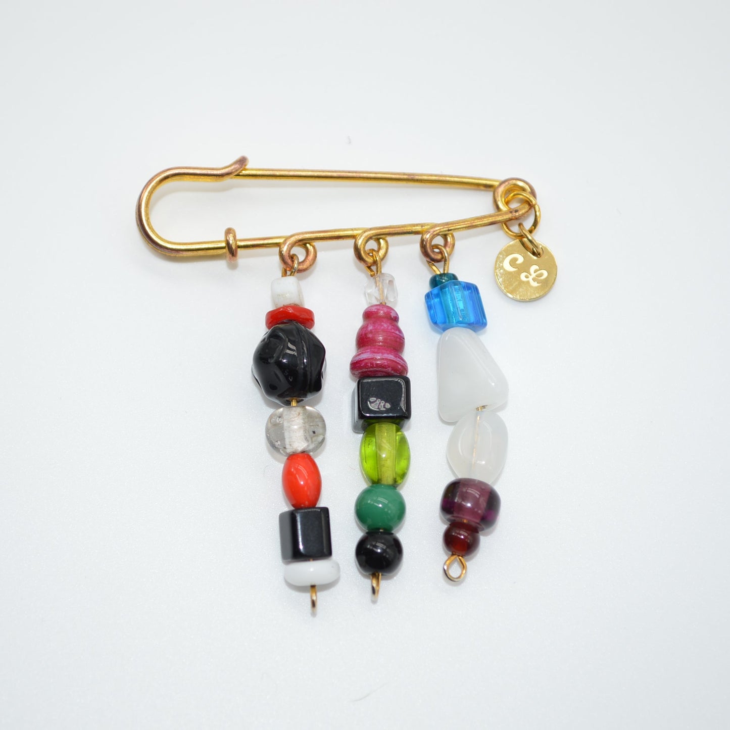 Gold safety pin with colorful beads on a white background