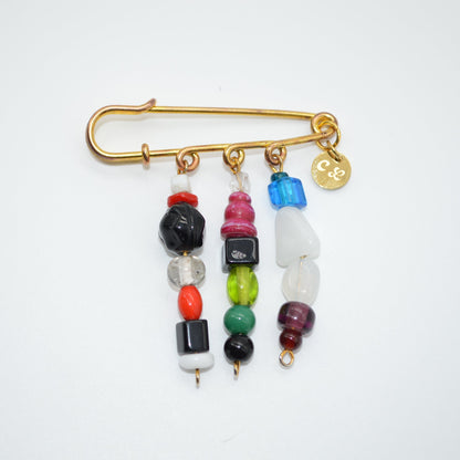 Gold safety pin with colorful beads on a white background