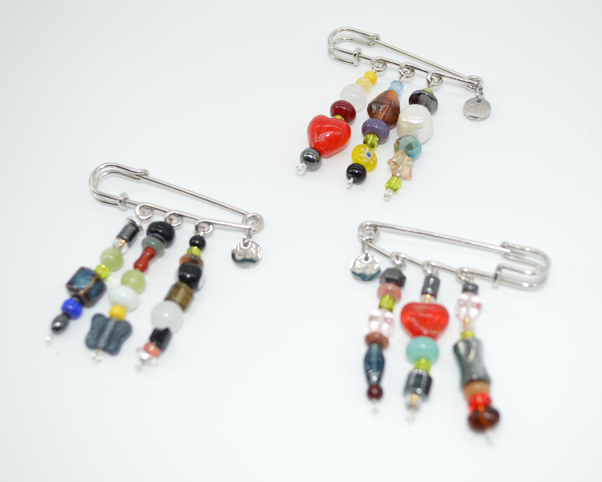 Three colorful beaded brooches on a white background