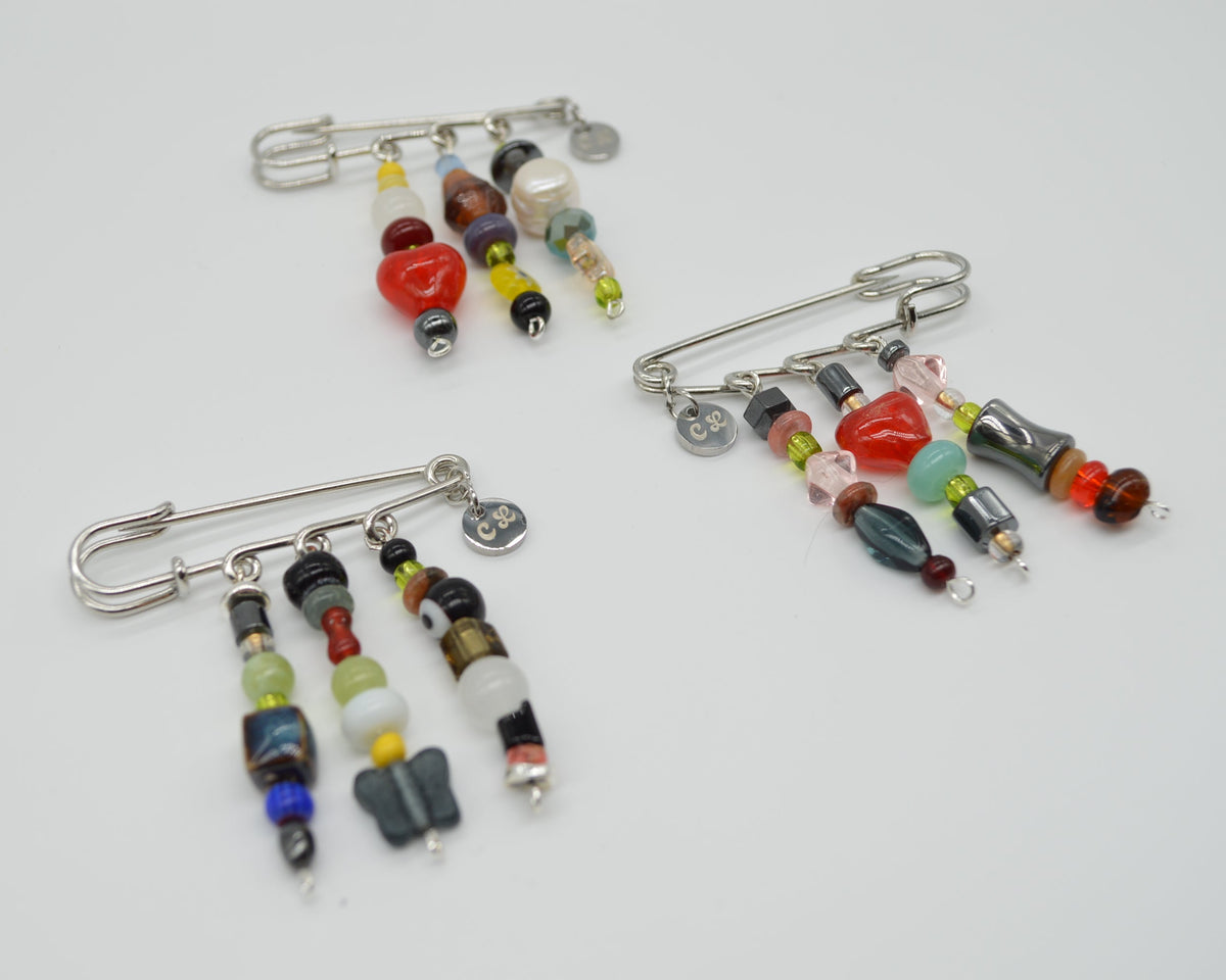 Three colorful beaded safety pins on a white background