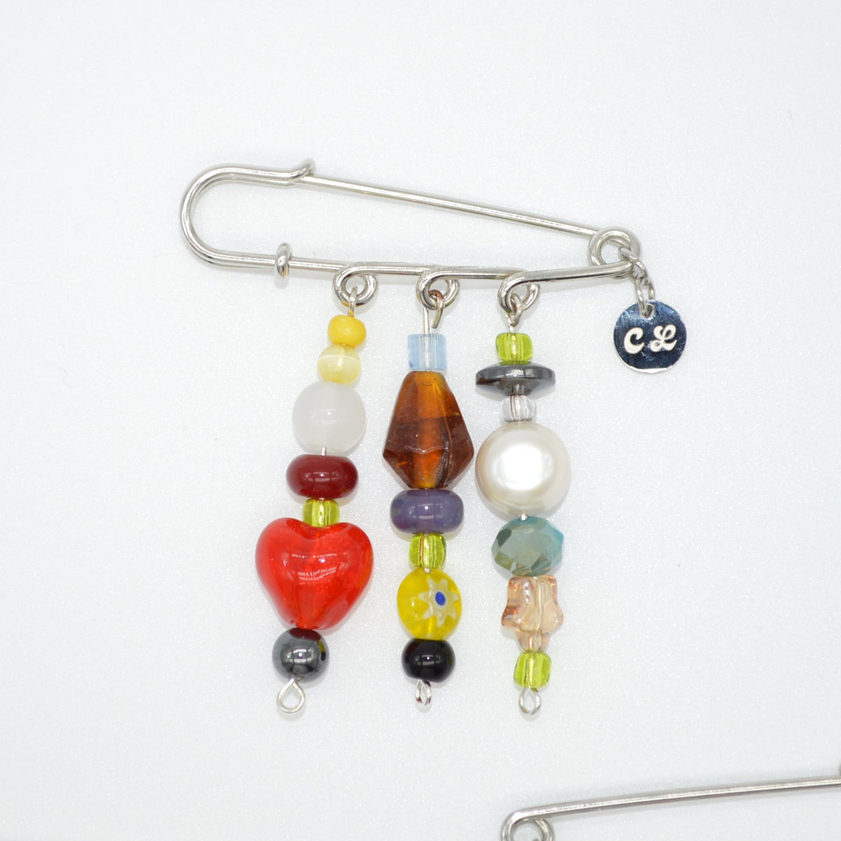 Colorful beaded brooch with a safety pin on a white background