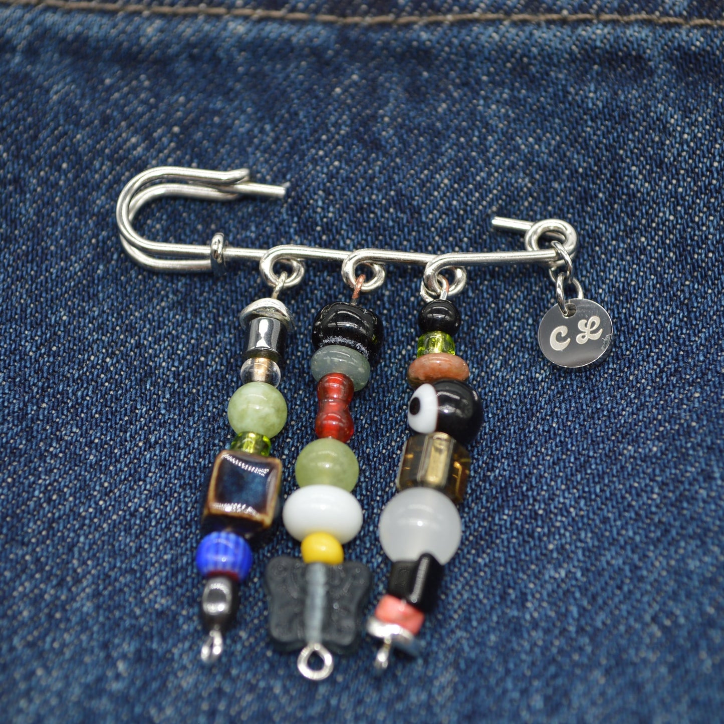 Beaded earring with colorful beads and metal components on a denim background
