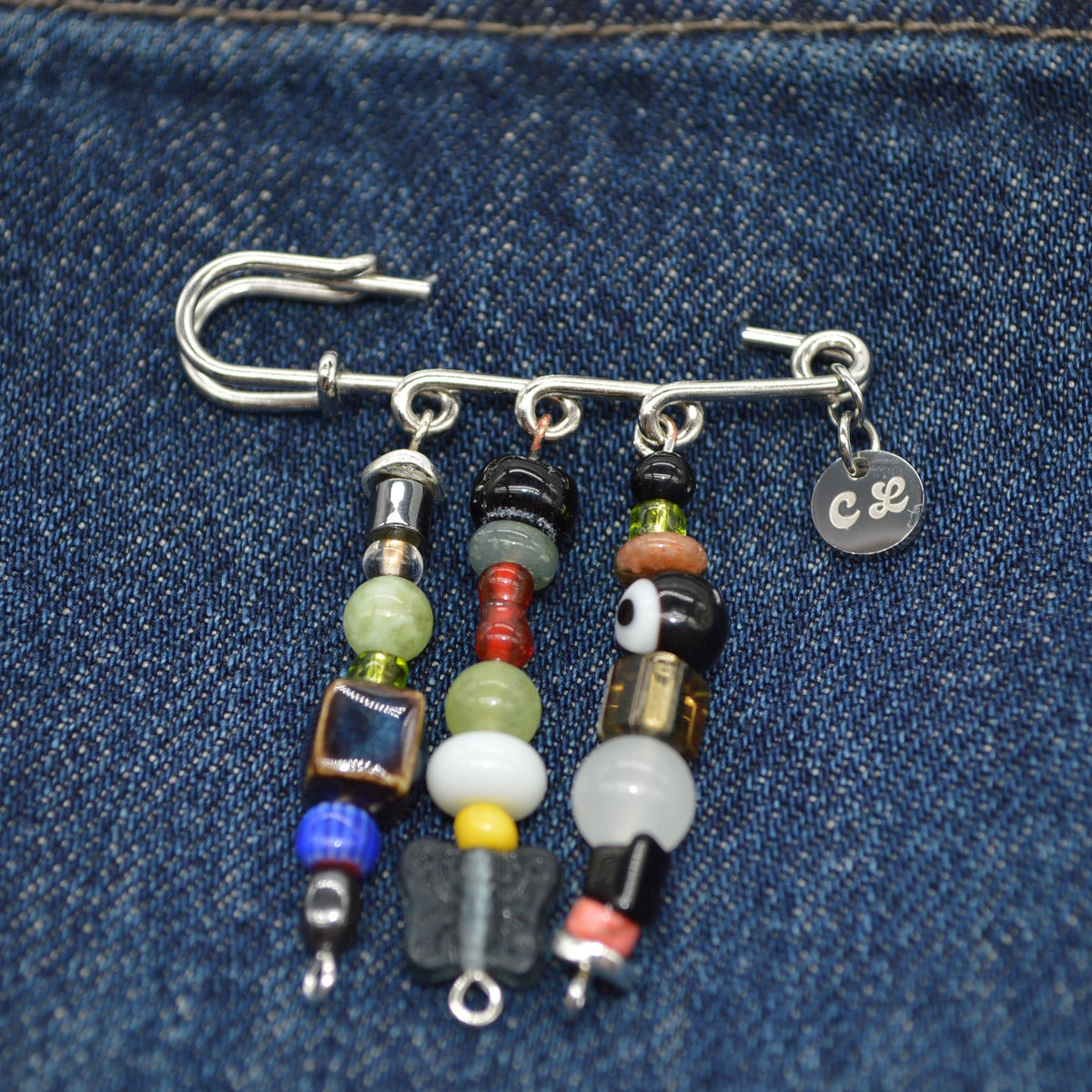 Beaded earring with colorful beads and metal components on a denim background