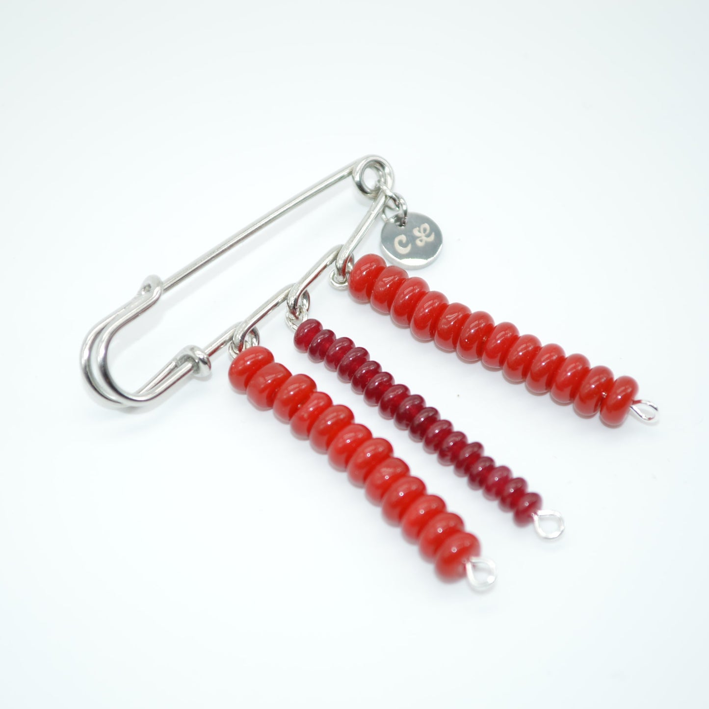 Red beaded earrings with a safety pin on a white background