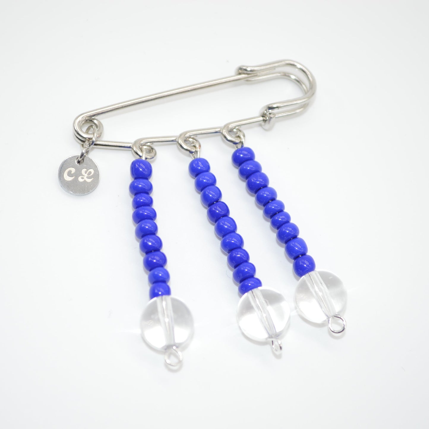 Silver safety pin with blue beads on a white background
