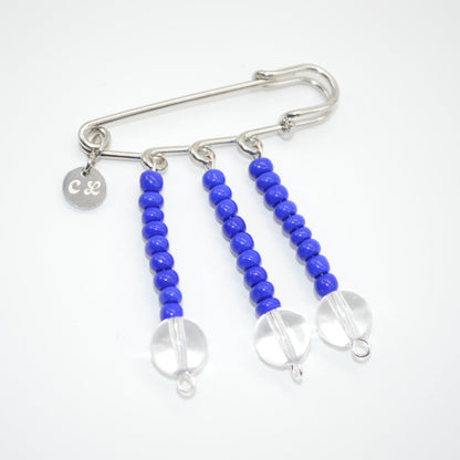 Silver safety pin with blue beads on a white background