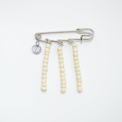 Brooch with safety pin and beaded extensions on a white background