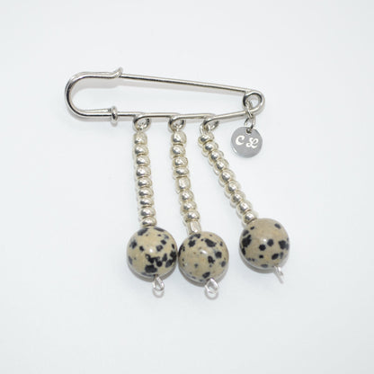 Silver brooch with three dangling balls on a white background