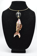 Jewelry display with a fish-shaped pendant on a black stand.