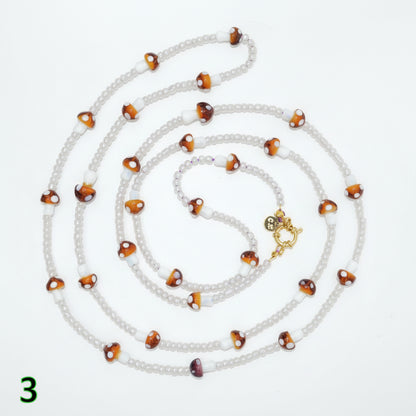 Beaded necklace with alternating white and brown beads on a light gray background
