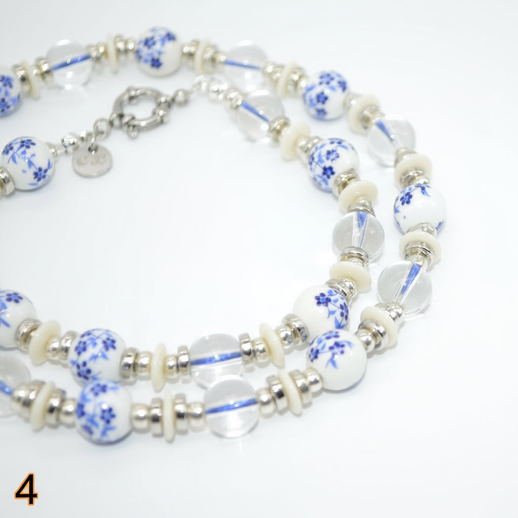 Beaded necklace with blue floral patterns on a white background