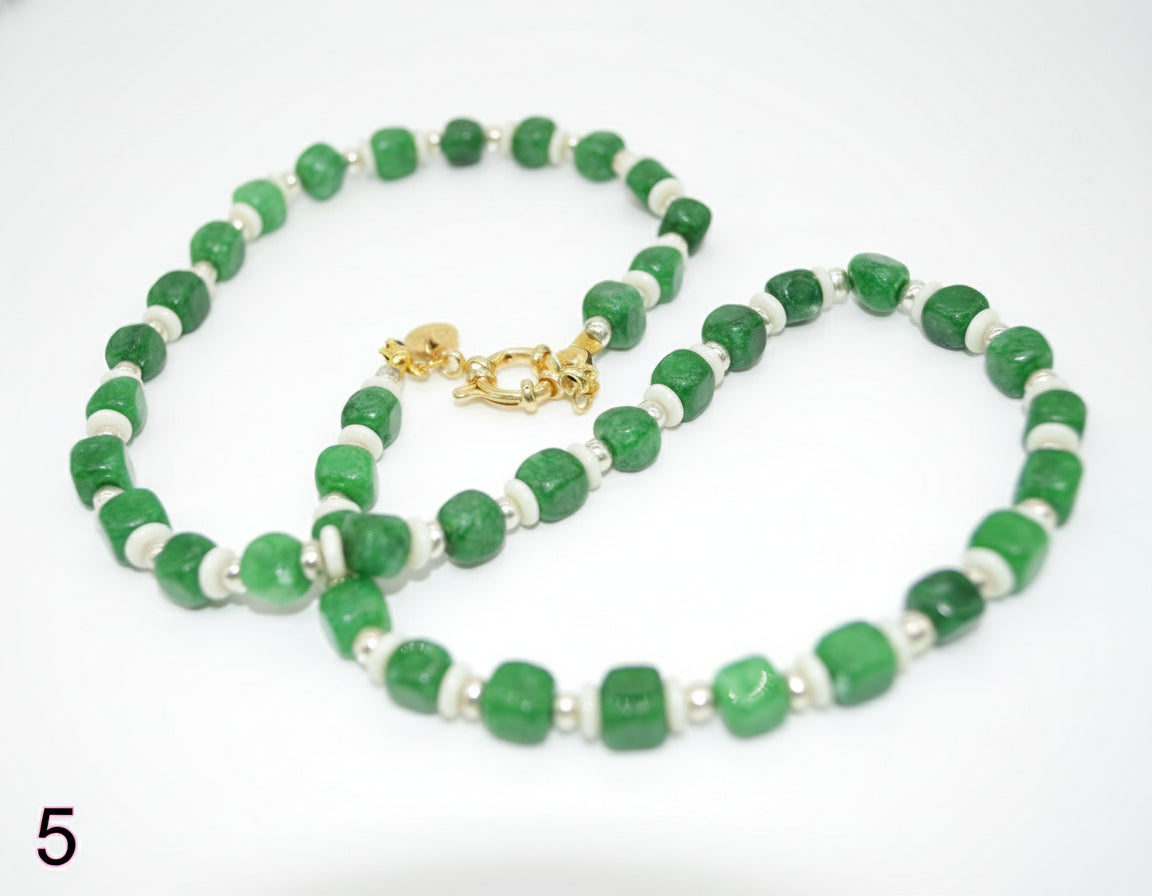 Green and white beaded necklace with a gold clasp on a white background