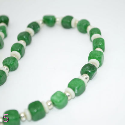 Necklace with green beads and a gold clasp on a white background