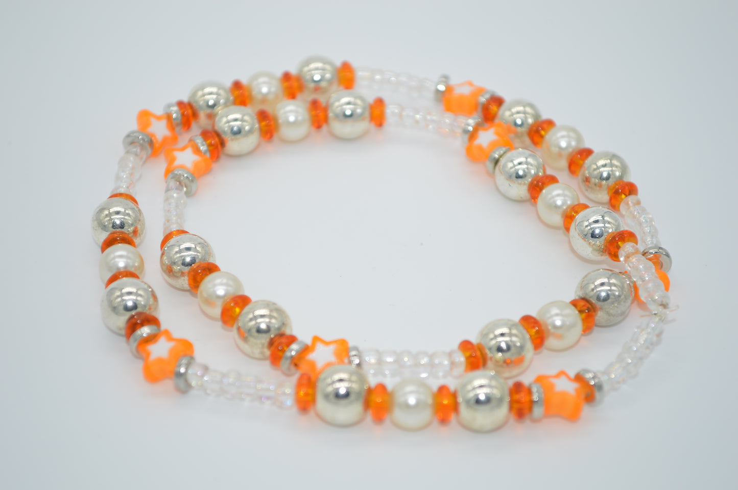 Beaded necklace with white, orange, and silver beads on a light gray background
