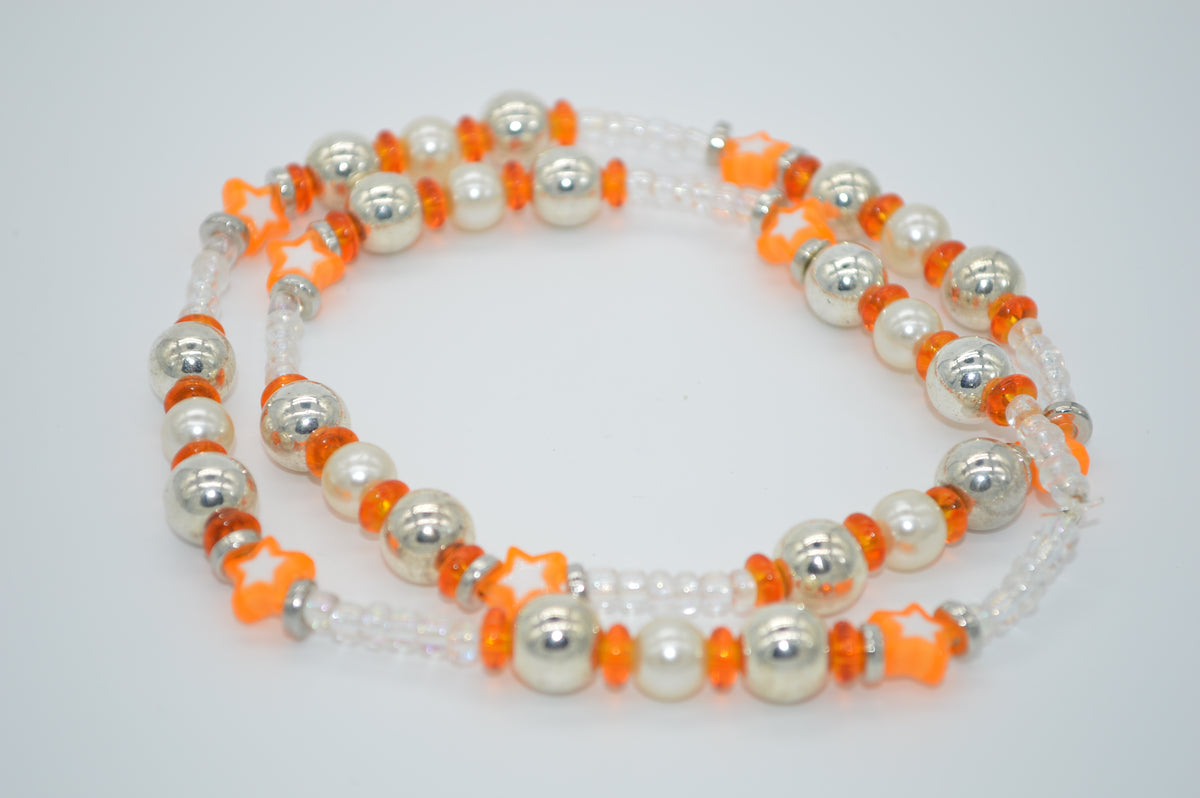 Beaded necklace with white, orange, and silver beads on a light gray background