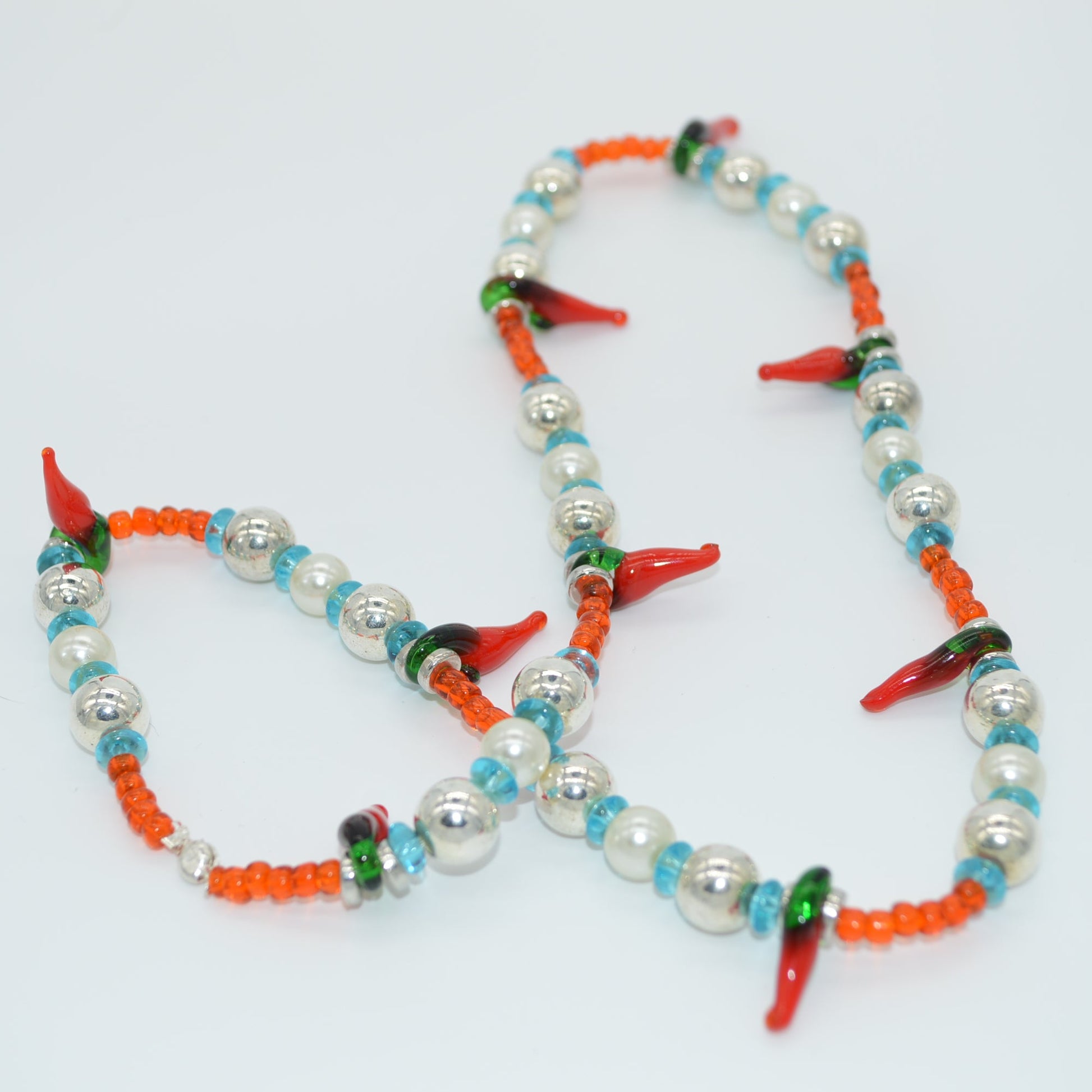 Colorful beaded necklace with red, green, and orange accents on a white background