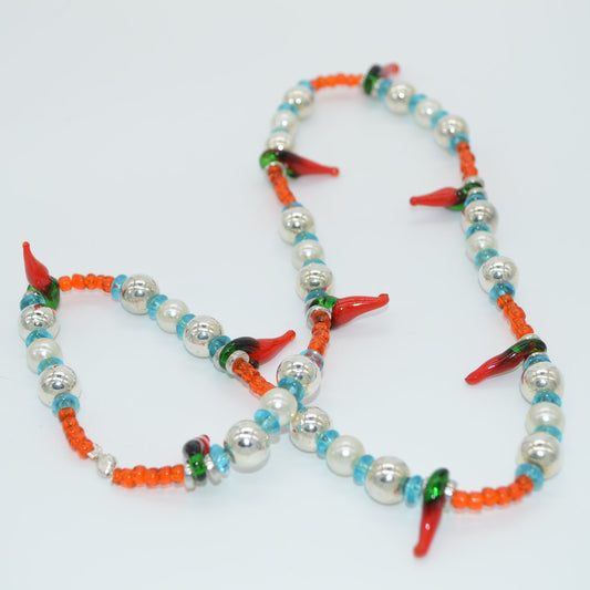 Colorful beaded necklace with red, green, and orange accents on a white background