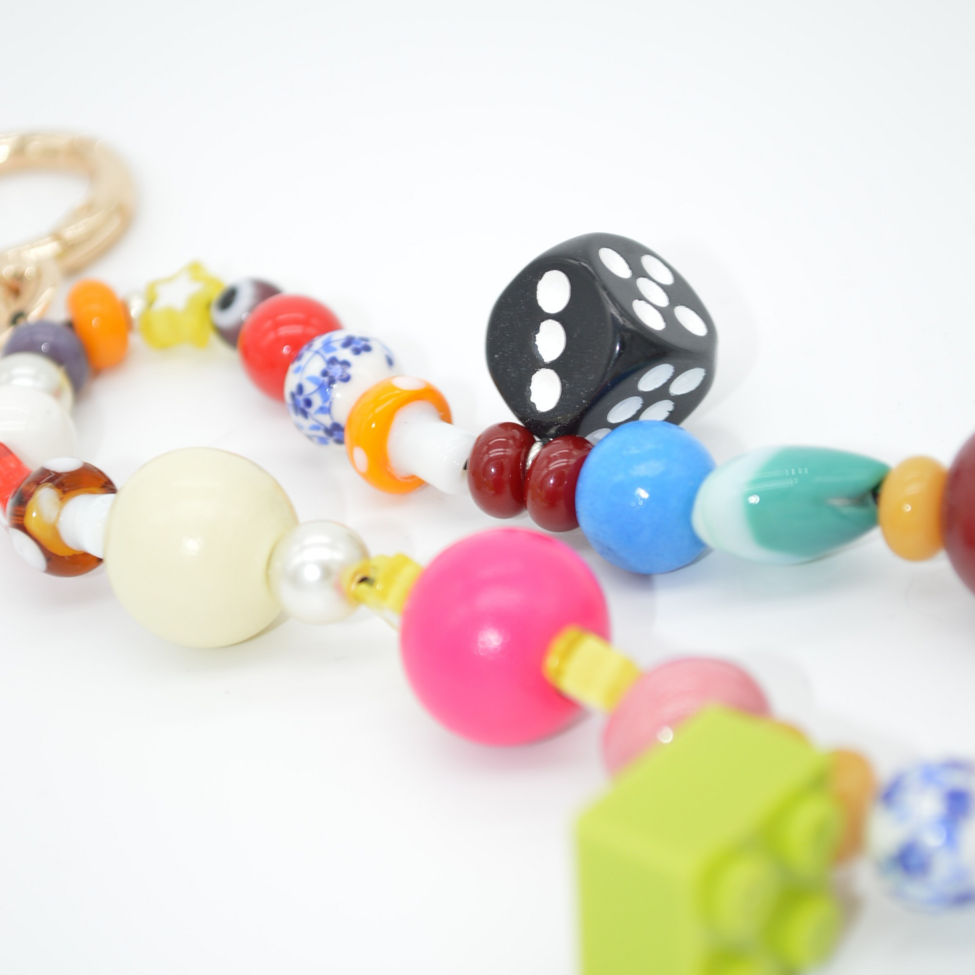 Colorful bead necklace with dice and block toy on a white background