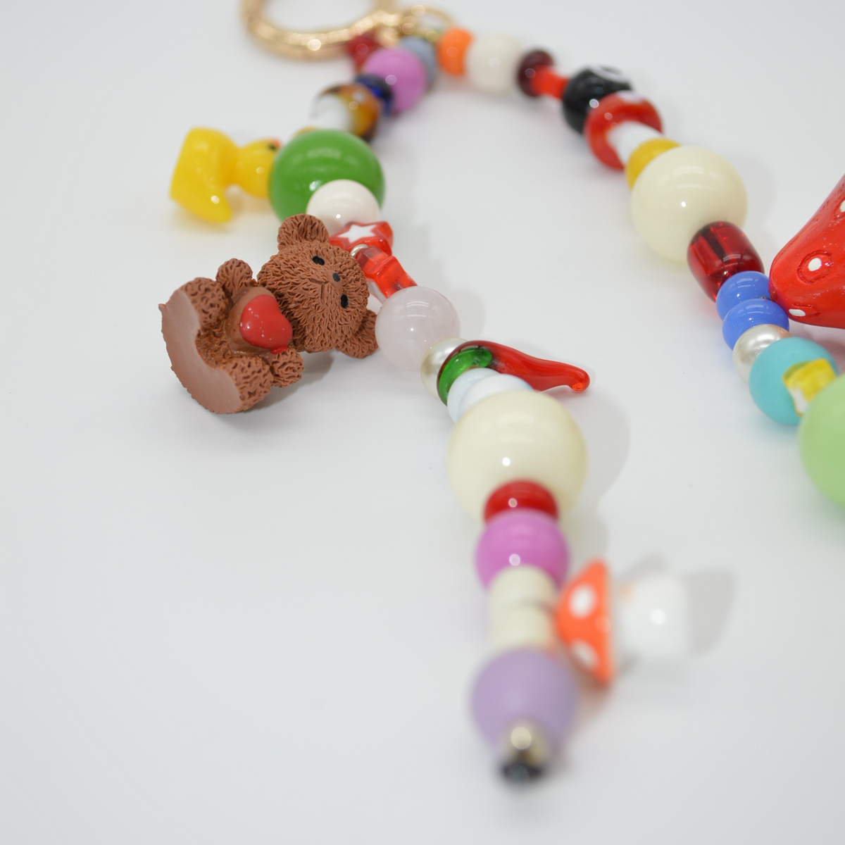 Colorful beaded keychain with a teddy bear charm on a light gray background