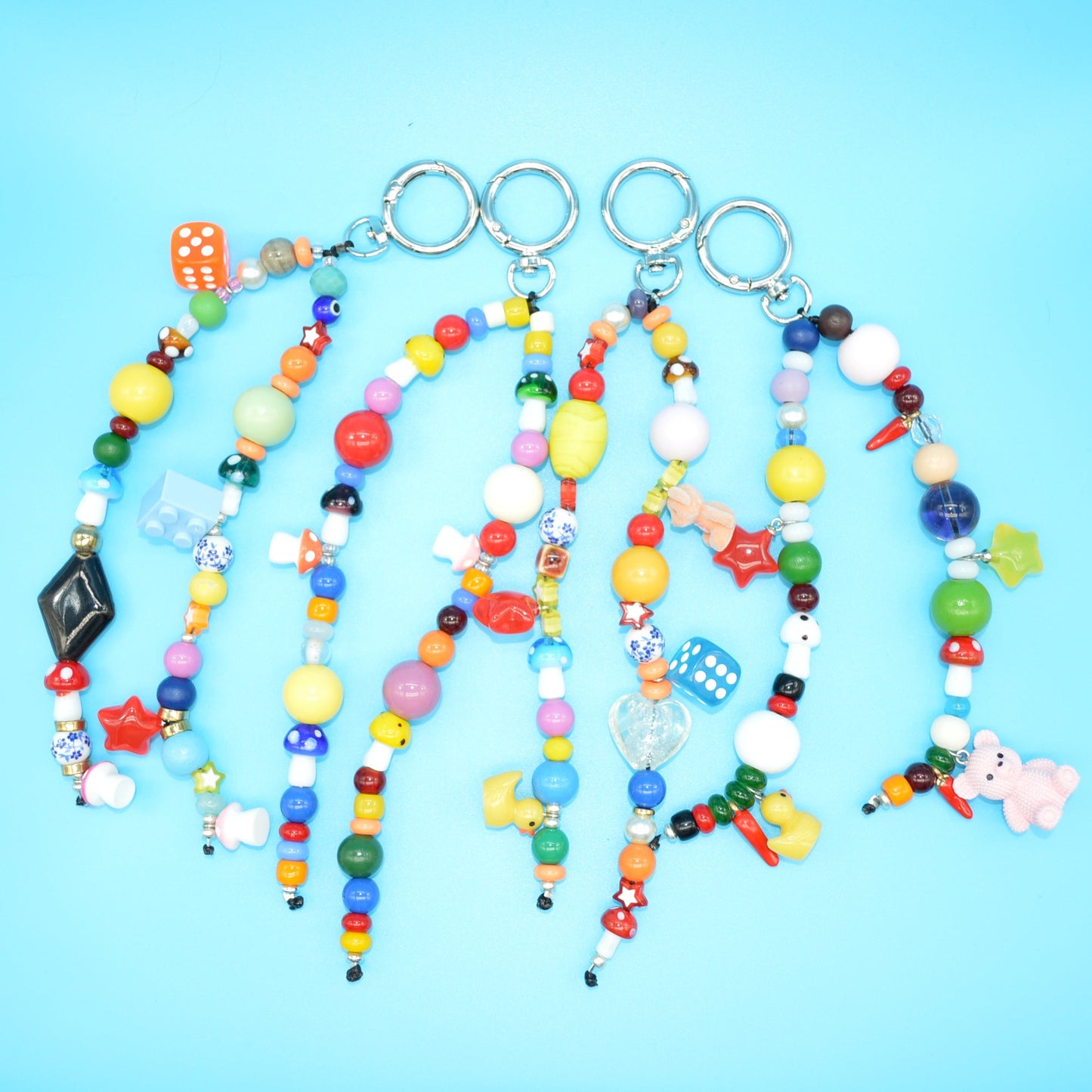 Colorful beaded keychains with various charms on a blue background