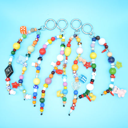 Colorful beaded keychains with various charms on a blue background