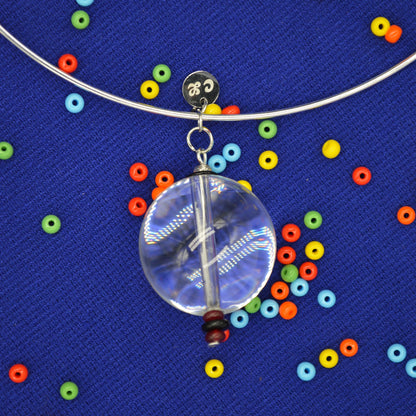 Clear glass orb with colorful beads on a blue textured background